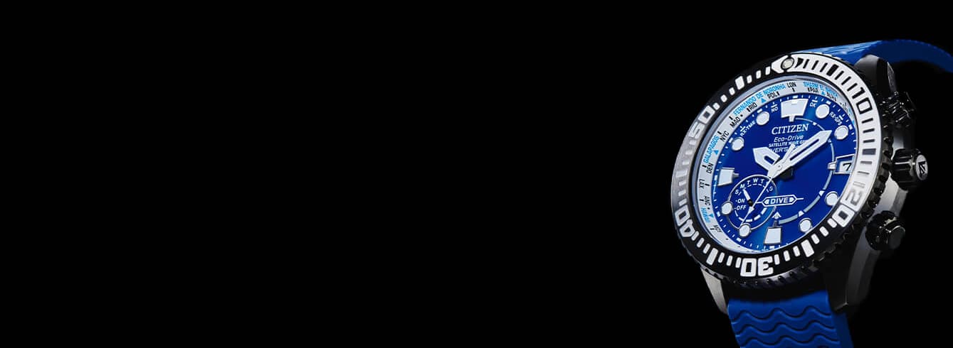 Blå dykkerklokke med skinnende svart og hvit kant, selvlysende markører og en blå gummirem, vist mot en helsvart bakgrunn.