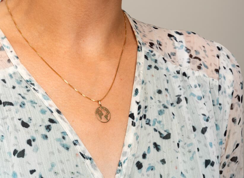 Kvinne iført en hvit- og blåsprekket bluse og et gullkjede med et sirkulært anheng.